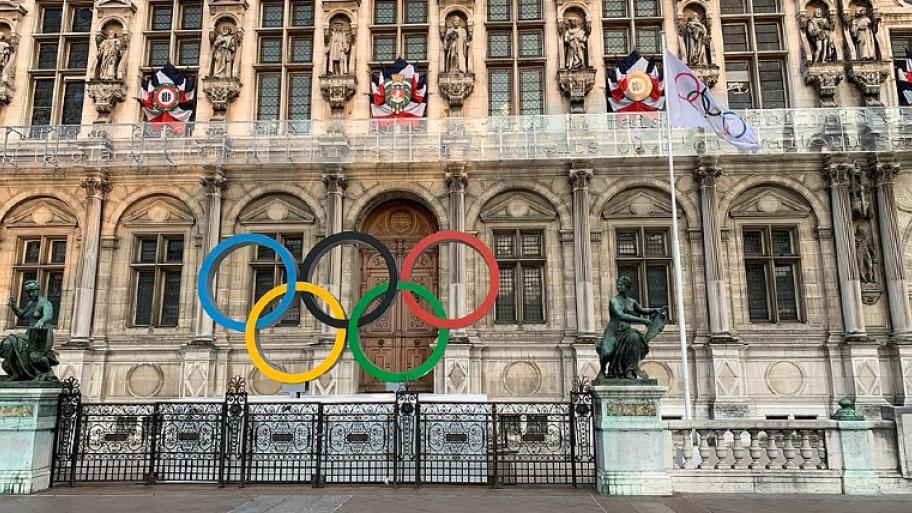 Hier sieht man ein Hotel in Paris. davor sind die Ringe von der Olympiade aufgebaut. Von links nach rechts mir den Farben: blau, gelb, schwarz, grün und rot.